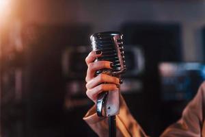 Close up view of microphone. Young beautiful female performer rehearsing in a recording studio photo