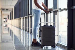 vista de partículas de una joven pasajera afroamericana con ropa informal que está en el aeropuerto con equipaje foto