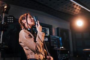 Young beautiful female performer sings and rehearsing in a recording studio photo