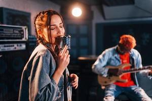 Guy plays guitar, girl sings. African american man with white girl rehearsing in the studio together photo