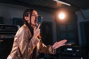 Young beautiful female performer sings and rehearsing in a recording studio photo