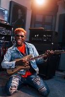 Plays guitar. Young african american performer rehearsing in a recording studio photo