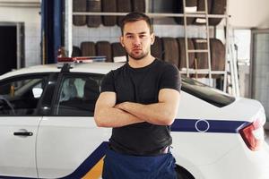Portrait of serious man that standing with arms crossed indoors against police car photo