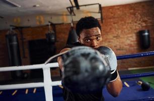 fuerte boxeador afroamericano con ropa deportiva tiene práctica en el gimnasio foto