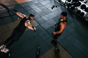 Personal trainer is on job. African american man with white guy have workout day in gym photo