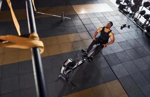 Strong african american man in sportive clothes have workout day in the gym and using equipment. Conception of power and strength photo