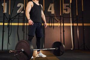 Strong man in sportive clothes lifting barbell in the gym photo