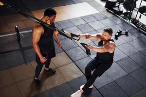 entrenador personal está en el trabajo. un hombre afroamericano con un hombre blanco tiene un día de entrenamiento en el gimnasio foto