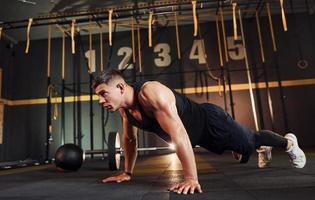 Strong man in sportive clothes doing push-ups in the gym photo