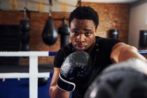 Strong african american boxer in sportive clothes have practice in the gym photo