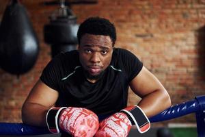 fuerte boxeador afroamericano con ropa deportiva tiene práctica en el gimnasio foto