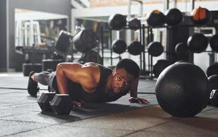 Strong african american man in sportive clothes doing push-ups in the gym photo