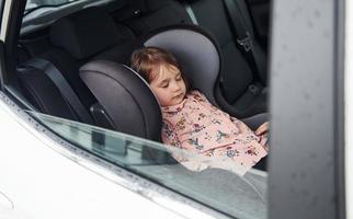 Cute little girl sleeping inside of the car. Conception of traveling and vaccation photo