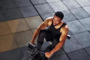 Strong african american man in sportive clothes have workout day in the gym and using equipment. Conception of power and strength photo