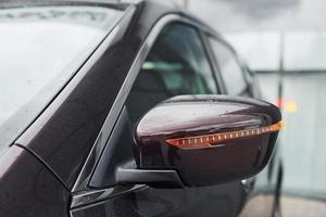 Front particle view of black modern automobile. Side mirror photo