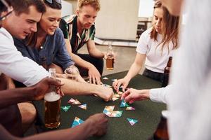 Playing card game. Group of young people in casual clothes have a party at rooftop together at daytime photo