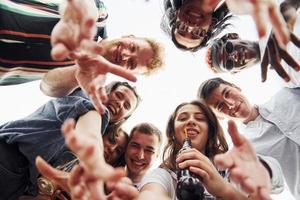 mirando abajo. vista desde abajo. un grupo de jóvenes con ropa informal tienen una fiesta en la azotea juntos durante el día foto