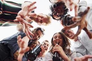 mirando abajo. vista desde abajo. un grupo de jóvenes con ropa informal tienen una fiesta en la azotea juntos durante el día foto