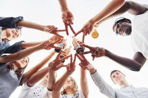 Making beautiful gesture by fingers. View from below. Group of young people in casual clothes have a party at rooftop together at daytime photo