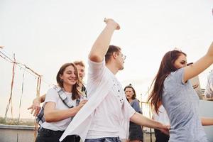 Recreation time. Group of young people in casual clothes have a party at rooftop together at daytime photo