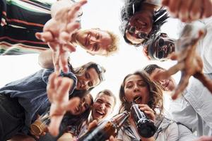 mirando abajo. vista desde abajo. un grupo de jóvenes con ropa informal tienen una fiesta en la azotea juntos durante el día foto