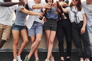 Standing with alcohol at the edge of rooftop. Group of young people in casual clothes have a party together at daytime photo