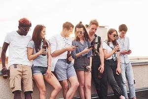 Cloudy weather. Group of young people in casual clothes have a party at rooftop together at daytime photo