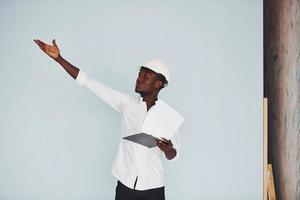 Young african american engineer in hardhat indoors with notepad in hands photo