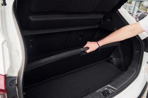 Woman's hands opening car trunk. Close up view. White modern automobile photo