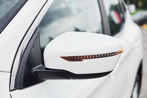 Front particle view of white modern automobile. Side mirror photo