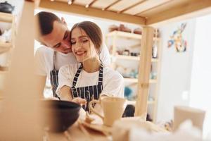 Job is done. With her boyfriend or husband. Young female ceramist indoors with finished handmade clay product. Conception of pottery photo