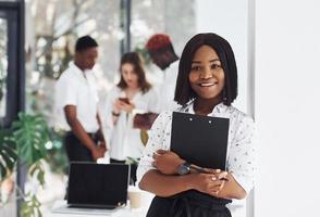 Holding notepad. Group of african american business people working in office together photo