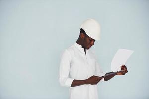 Young african american engineer in hardhat indoors with notepad in hands photo