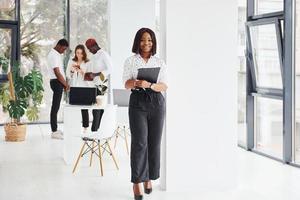 Woman holding notepad. Group of african american business people working in office together photo