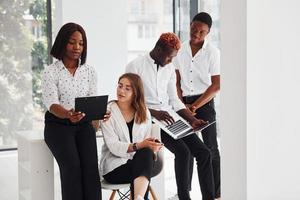 Busy and holding laptop and notepad. Group of african american business people working in office together photo