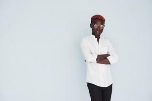 Young african american man in white formal clothes standing against wall indoors photo