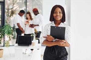 Woman holding notepad. Group of african american business people working in office together photo