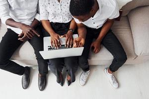 Comfortable sofa. Using laptop. Group of african american business people working when sitting together photo