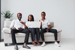 Comfortable sofa. Using laptop. Group of african american business people working when sitting together photo