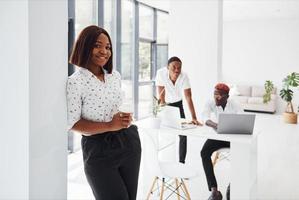 Beautiful woman standing in front of colleagues. Group of african american business people working in office together photo