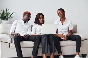 Comfortable sofa. Using laptop. Group of african american business people working when sitting together photo