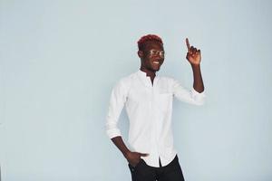 Young african american man in white formal clothes standing against wall indoors photo