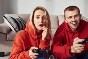 Young lovely couple together at home playing video games at weekend and holidays time together photo