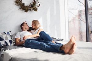 Young lovely couple lying down on bed together at home spending weekend and holidays together photo