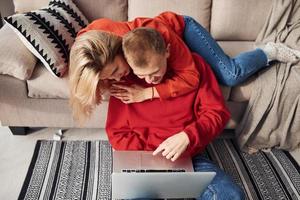 Using laptop that is on the legs. Young lovely couple together at home spending weekend and holidays together photo
