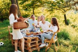 mujer sosteniendo una cesta con comida. grupo de jóvenes tiene vacaciones al aire libre en el bosque. concepción de fin de semana y amistad foto