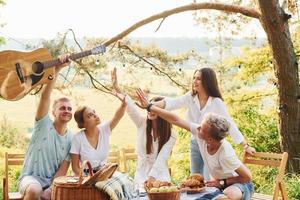 Giving high five to each other. Group of young people have vacation outdoors in the forest. Conception of weekend and friendship photo