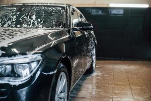 automóvil negro moderno estacionado dentro de la estación de lavado de autos foto
