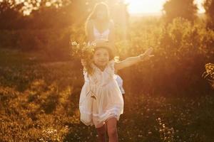hermoso rayo de luz. madre con niño y niña pasando tiempo libre en el campo en un día soleado de verano foto