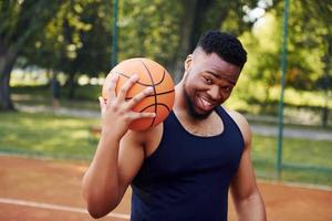 African american man standing with ball on the court outdoors photo
